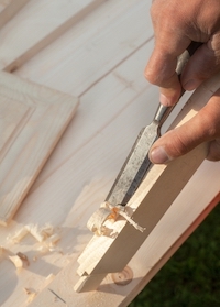 A wood chisel shaving pieces off a wood block.