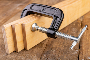 A C-clamp used while gluing wood planks together.