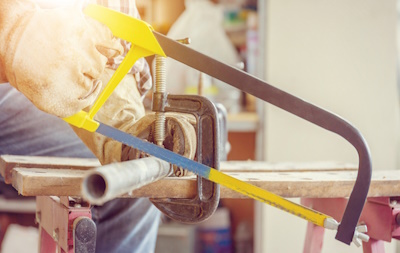 Hacksaw cutting through a steel pipe.