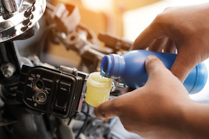 A mechanic adds hydraulic fluid to a vehicle's brake system.