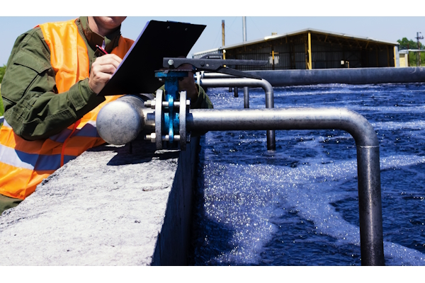 Un employé inspecte visuellement une vanne dans un système de filtration d'eau.