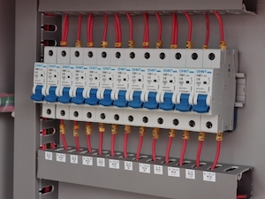 A row of miniature circuit breakers mount on an electrical switchboard.