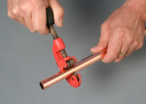 Using a pipe cutter to cut a copper pipe