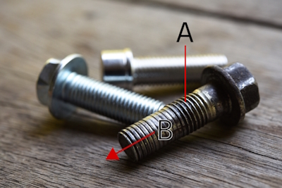 Start filing next to the damaged part of the thread (A), and move towards the damaged section and across it (B).