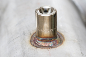 A coupling made of stainless steel 316L welded to a small diameter pressure vessel.